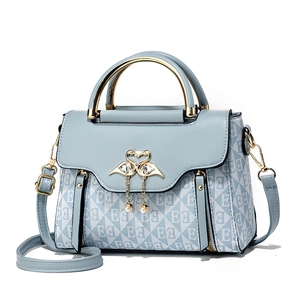 Borsa a tracolla azzurra con ornamento a cigno e ciondolo a perla su sfondo bianco