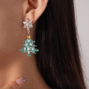Detail of Christmas earrings featuring silver snowflake and green tree with pearls