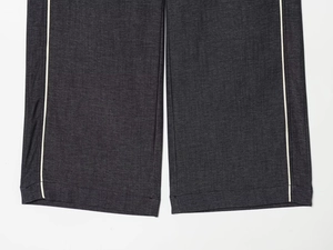 Détail du pantalon en jean gris foncé avec bandes latérales blanches et ourlet piqué