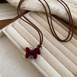 Detailed shot of a burgundy flocked rocking horse necklace with zircon in a jewelry box