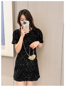 Close-up of a gold lip-shaped mini chain bag paired with a black sequin dress on a model