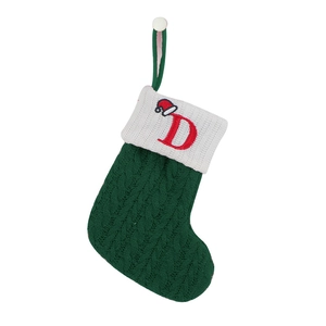Close-up of a green knitted Christmas stocking with an embroidered letter D and hat