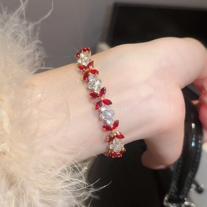 Detail of a gold flower bracelet featuring alternating red marquise and white round gemstones