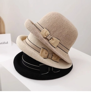 Tre cappelli da sole in maglia con nastri a fiocco in nero, beige e giallo impilati