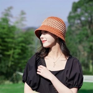 Detail of orange and beige woven knit bucket hat with hollow stitch design on model