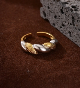 Macro view of S925 silver braided twist ring with gold accent on dark suede
