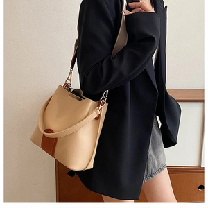 Close-up of beige and brown bucket bag with metallic details on a black blazer