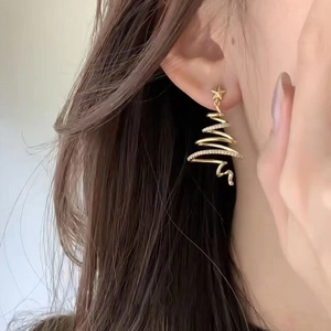 Close-up of a model wearing a gold Christmas tree stud earring with shiny zircon stones