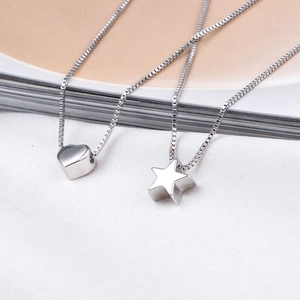 Detail view of silver necklaces with 3D heart and star pendants on white fabric