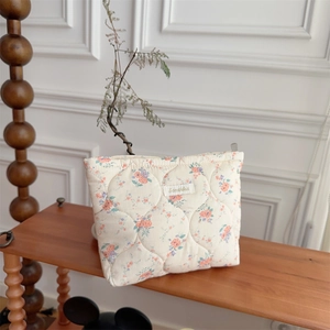Quilted floral cotton cosmetic bag with rose patterns on a cozy vintage shelf background