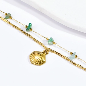 Close-up of golden double-layer anklet with seashell charm and blue stone beads