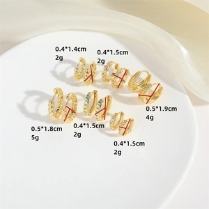 Modern gold twisted hoop earrings set with zircon and turquoise on a white display