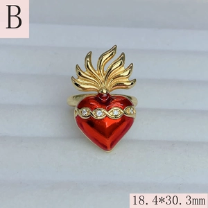 Detailed close-up of red enamel sacred heart ring with gold wings and zircon accents