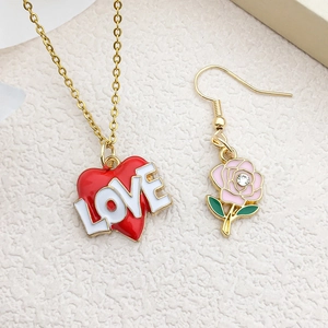 Detail of red enamel LOVE heart pendant and pink rose earring with gold metal finish