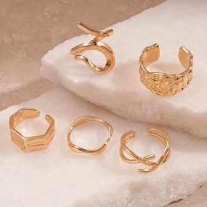 Five-piece gold geometric ring set with hammered and wavy designs on white stone