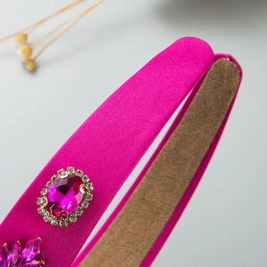 Close-up of rose red satin headband featuring ornate pink crystals and sparkling rhinestones