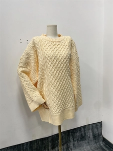 Détail du pull en maille épaisse beige avec motifs torsadés et texture losange