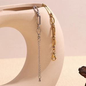Detail of gold and silver paperclip link bracelets with lobster clasp on beige vase