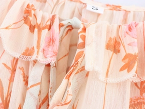 Detailaufnahme des floralen Chiffonkleides mit Rüschenausschnitt und Bindebändern