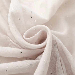 Close-up of soft beige gauze fabric with silver sequins and elegant draped texture