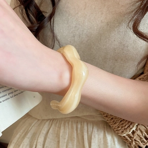 Irregular cream yellow acrylic wavy bangle shown worn with minimalist casual attire