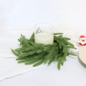 Close-up of realistic Norfolk Pine needle candle ring wreath on white fabric background