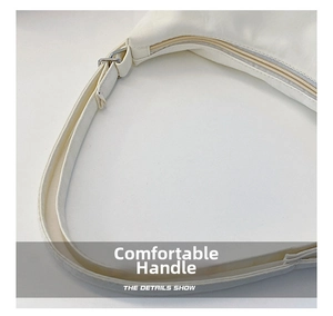 Detail shot of the adjustable wide strap and metal zipper on white shoulder bag