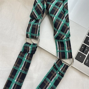 Detail of green plaid woven shoulder strap with silver metal rings on a tote bag