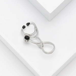 Macro shot of silver stethoscope brooch with three black gemstones on a white background