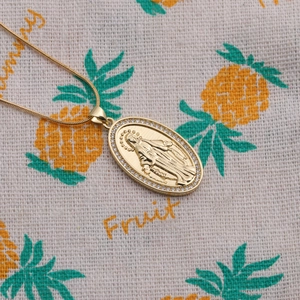 Detailed close-up of Virgin Mary oval pendant with micro-pave zircons and gold snake chain