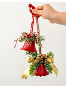 Detail of Christmas ornament with red bells, pine cones, and Merry Christmas ribbon