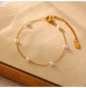 Detail of gold titanium steel bracelet with elegant white pearls and S steel tag