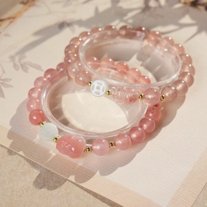 Detail of pink strawberry quartz beaded bracelets with golden spacers and carved charm