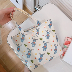 Detail of a printed canvas tote bag featuring cute blue rabbits and simple wish label