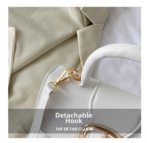 Detail of white lychee leather texture and golden detachable strap hook on handbag