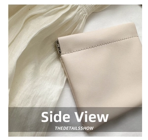 Detail view of cream leather mini pouch showing fine stitching and metal hinge closure