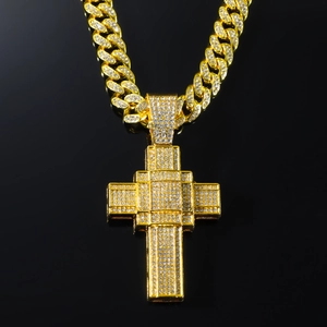 Close-up of golden iced-out cross pendant with diamond crystals on a cuban link chain