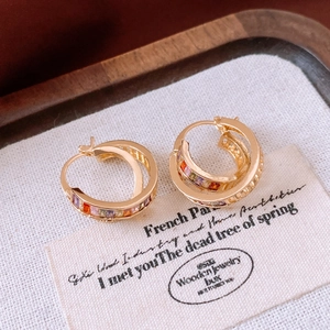 Macro shot of gold-plated square hoop earrings with rainbow gradient rectangle zircon stones