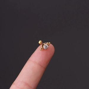 Macro shot of gold stainless steel stud earring with a clear zircon and gold bead details