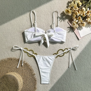 Détail du bas de bikini blanc avec anneaux métalliques dorés et liens sur les côtés