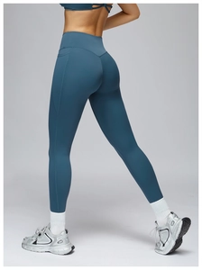 Detailed side view of high-waisted yoga pants with functional side pockets in dark grey-blue