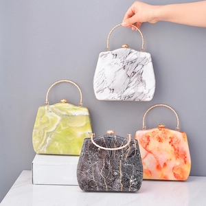 Detailed view of acrylic evening clutch bags with marble texture and gold round handles