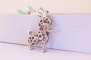 Close-up of a silver rhinestone-studded puppy pendant with a crown on a white box