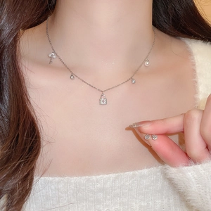Detail of silver necklace with key and lock charms, pearls, and matching stud earrings