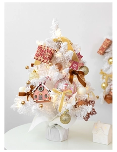 Detail of white mini Christmas tree with gingerbread man, red house, and warm LED lights