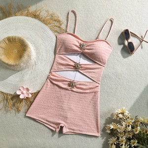 Detail of pink one-piece swimsuit featuring ruched fabric and gold sun-shaped crystal accents