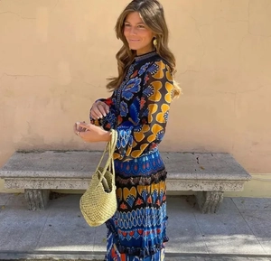 Detail of colorful floral maxi dress paired with a green woven bucket bag in a casual setting