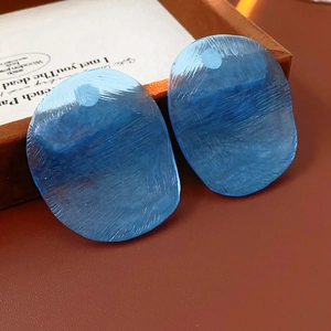 Detail of blue translucent irregular earrings with unique textured finish on leather