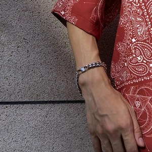 Silver cuban chain bracelet on wrist featuring flat metal links and a square clasp