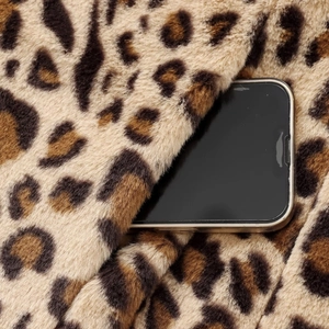Close-up of leopard print faux fur jacket fabric with soft plush texture and thick piles